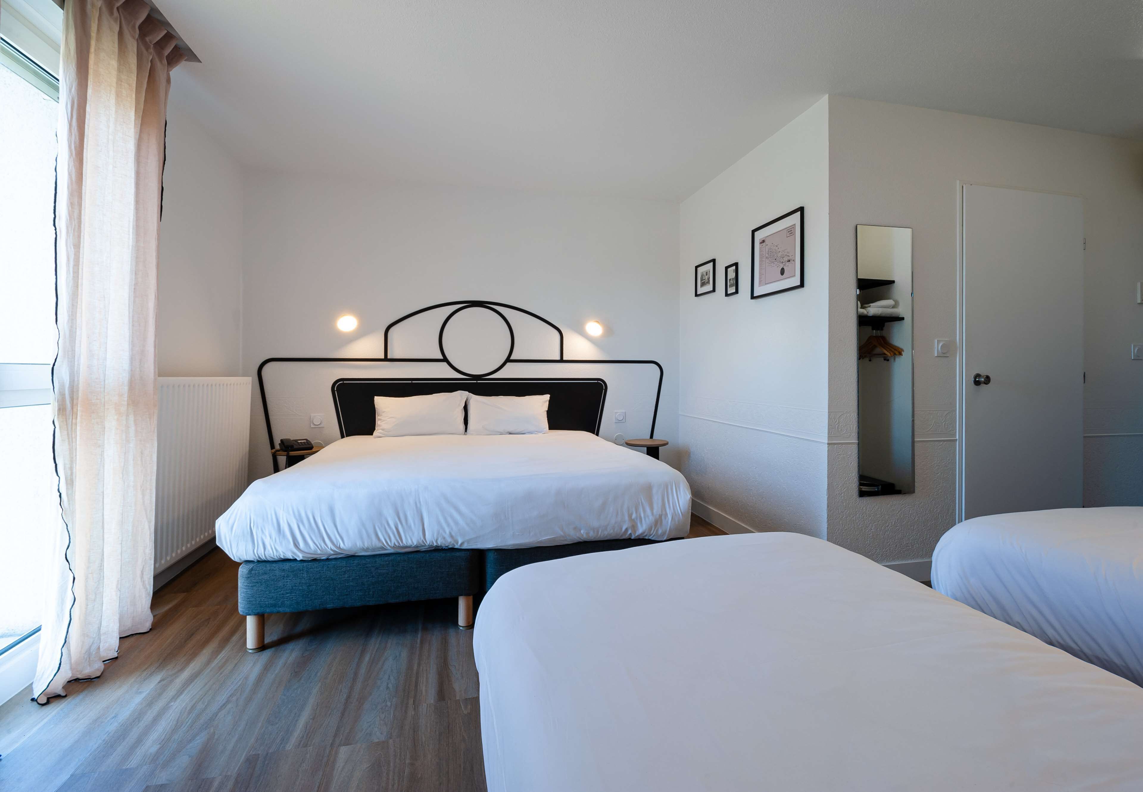 Una habitación de hotel con dos camas, una mesita de noche, un espejo y un radiador.
