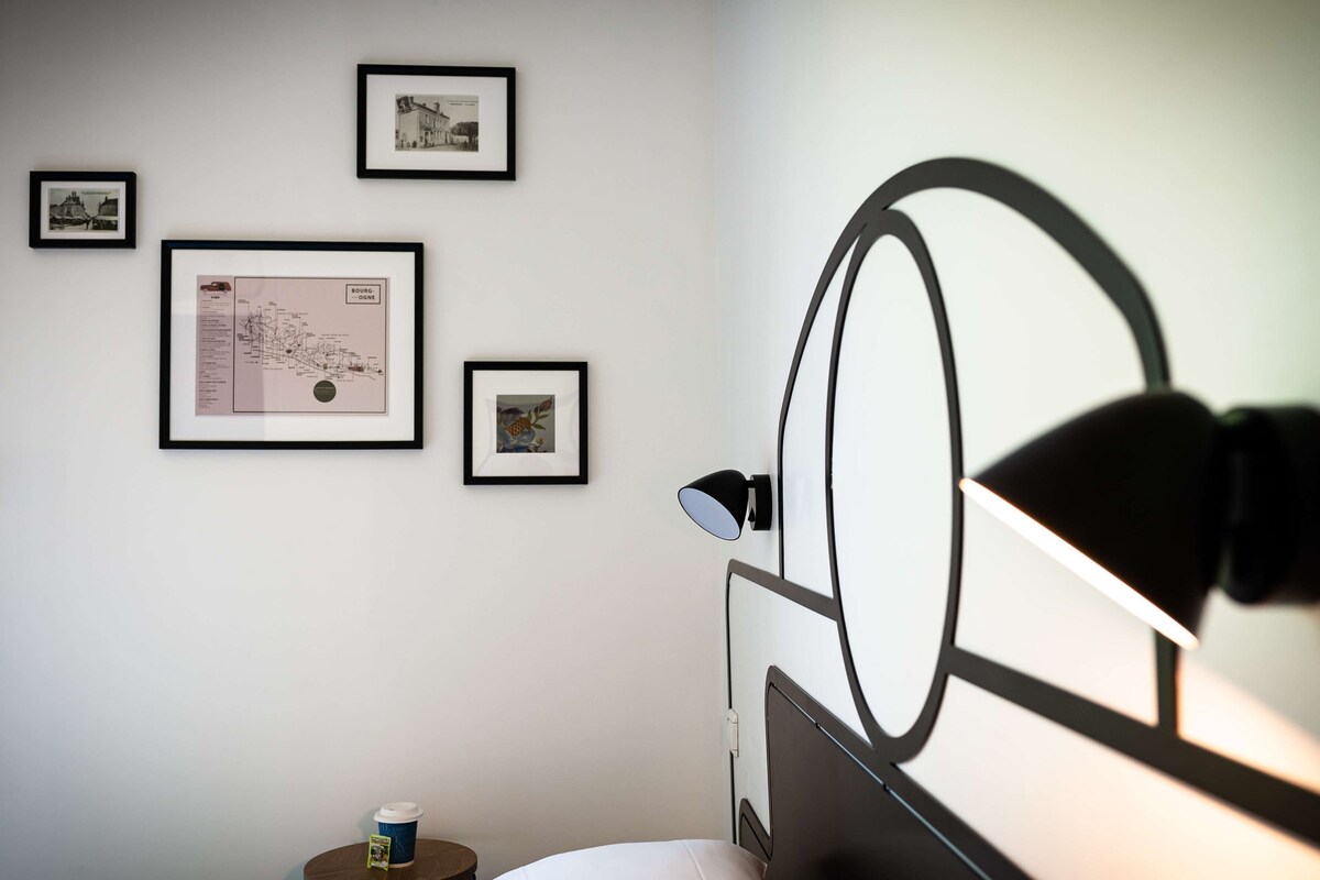Une chambre à coucher avec un lit, une lampe et des tableaux encadrés accrochés au mur.