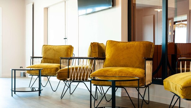 Una habitación moderna con tres sillas amarillas y una pequeña mesa redonda.