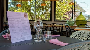 Une table de restaurant avec un menu, des verres à vin vides et une serviette rose.