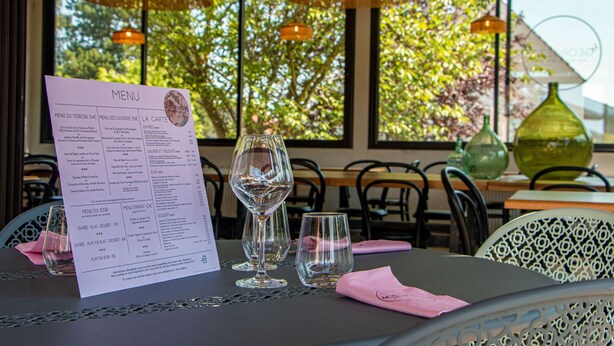 A restaurant table with a menu, empty wine glasses, and a pink napkin.