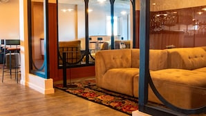 A modern interior with a sofa, chairs, and a bar area visible through a glass partition.