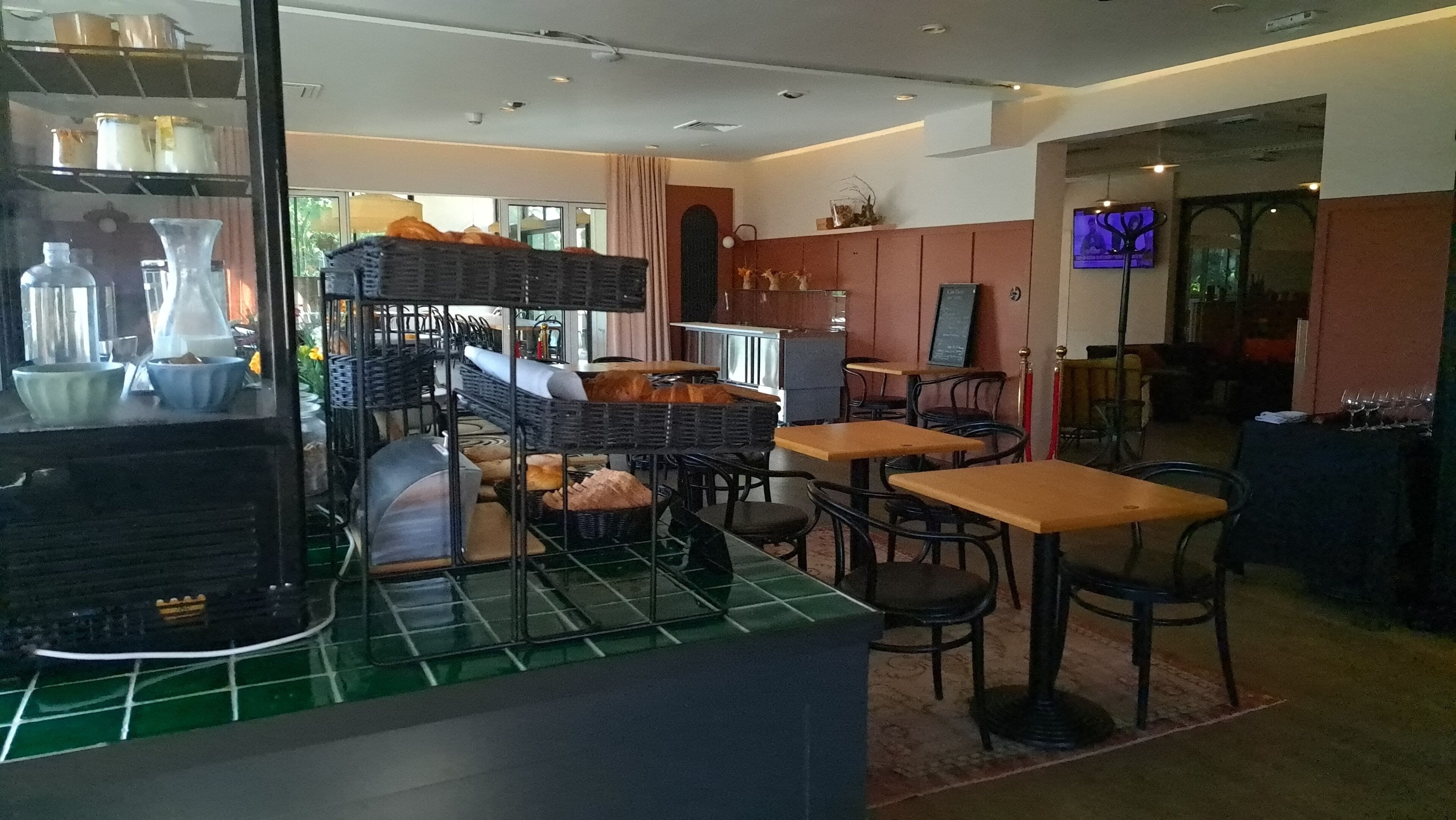 Un restaurante con zona de bar, asientos y una pantalla de televisión.