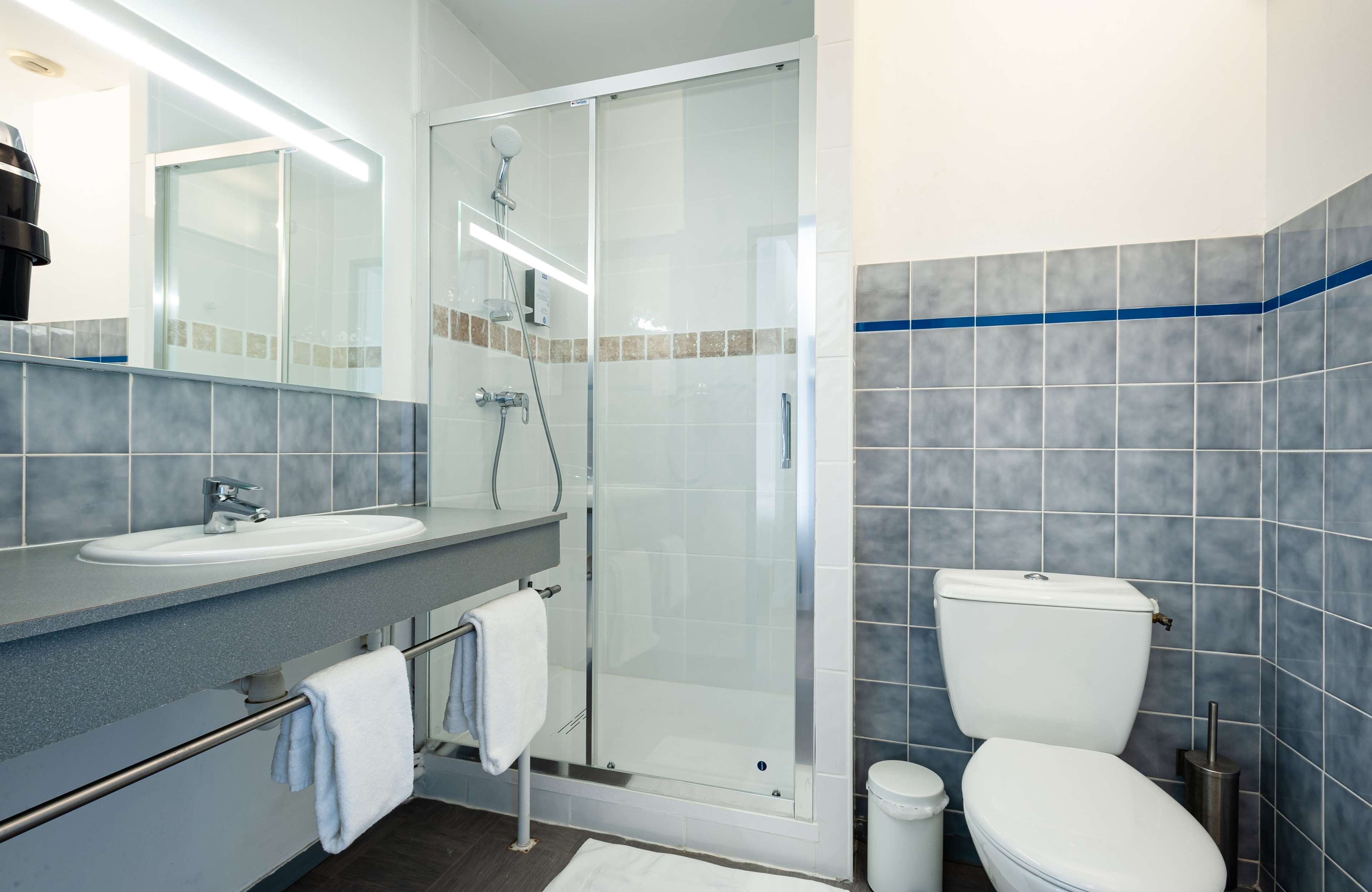Een moderne badkamer met een douchecabine van glas, een wit wastafelmeubel en een toilet.