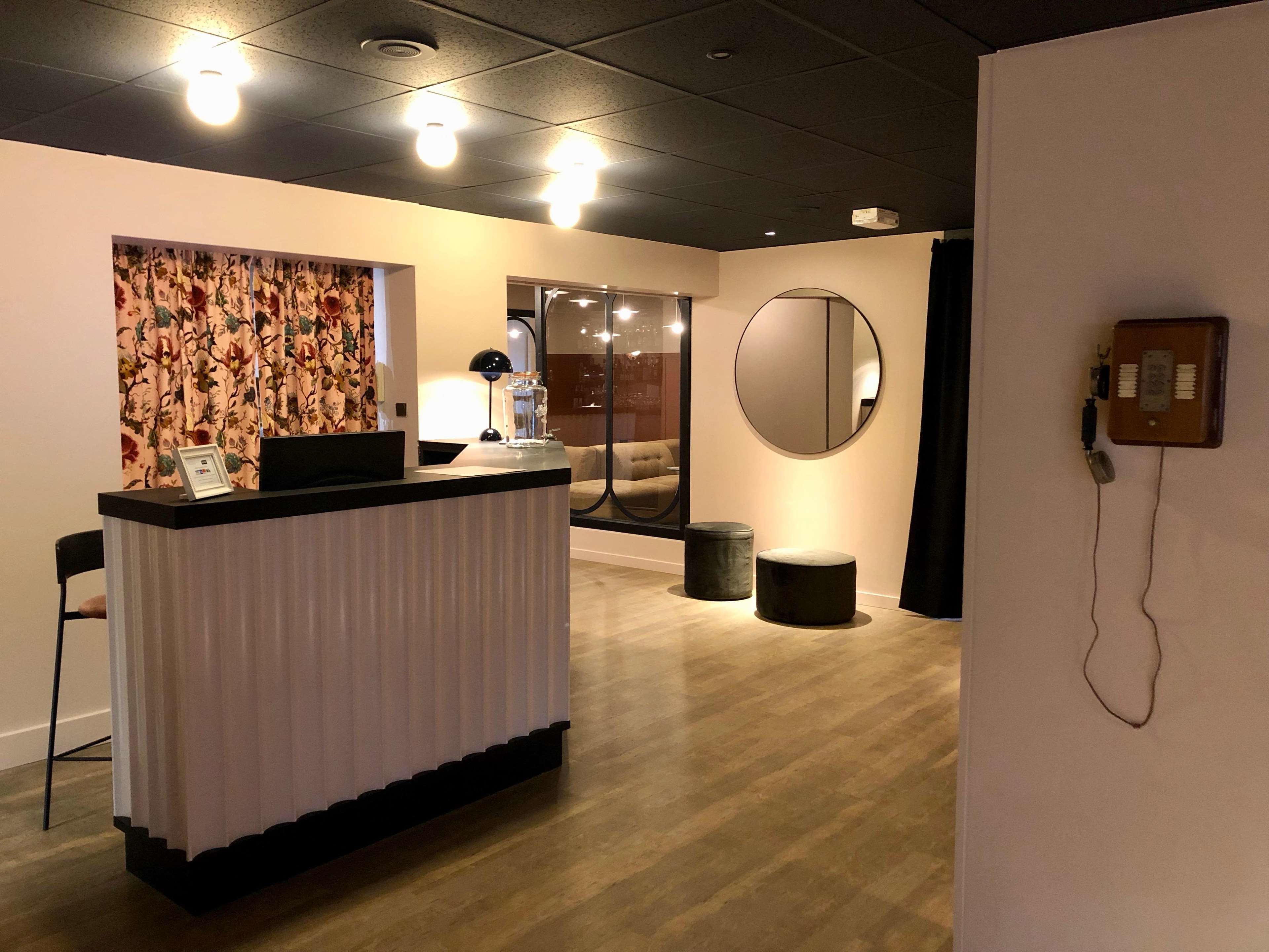 Un espace d’accueil comprenant un comptoir, un bureau, une lampe, un miroir et un téléphone.