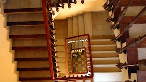 A grand staircase with ornate wooden railings and a central mirror reflecting the stairs. - Hostal Loreto (Denia)