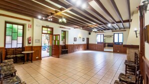 A spacious hall with wooden beams and tiled flooring, featuring a reception area with a counter and chairs. - Hostal Loreto (Denia)