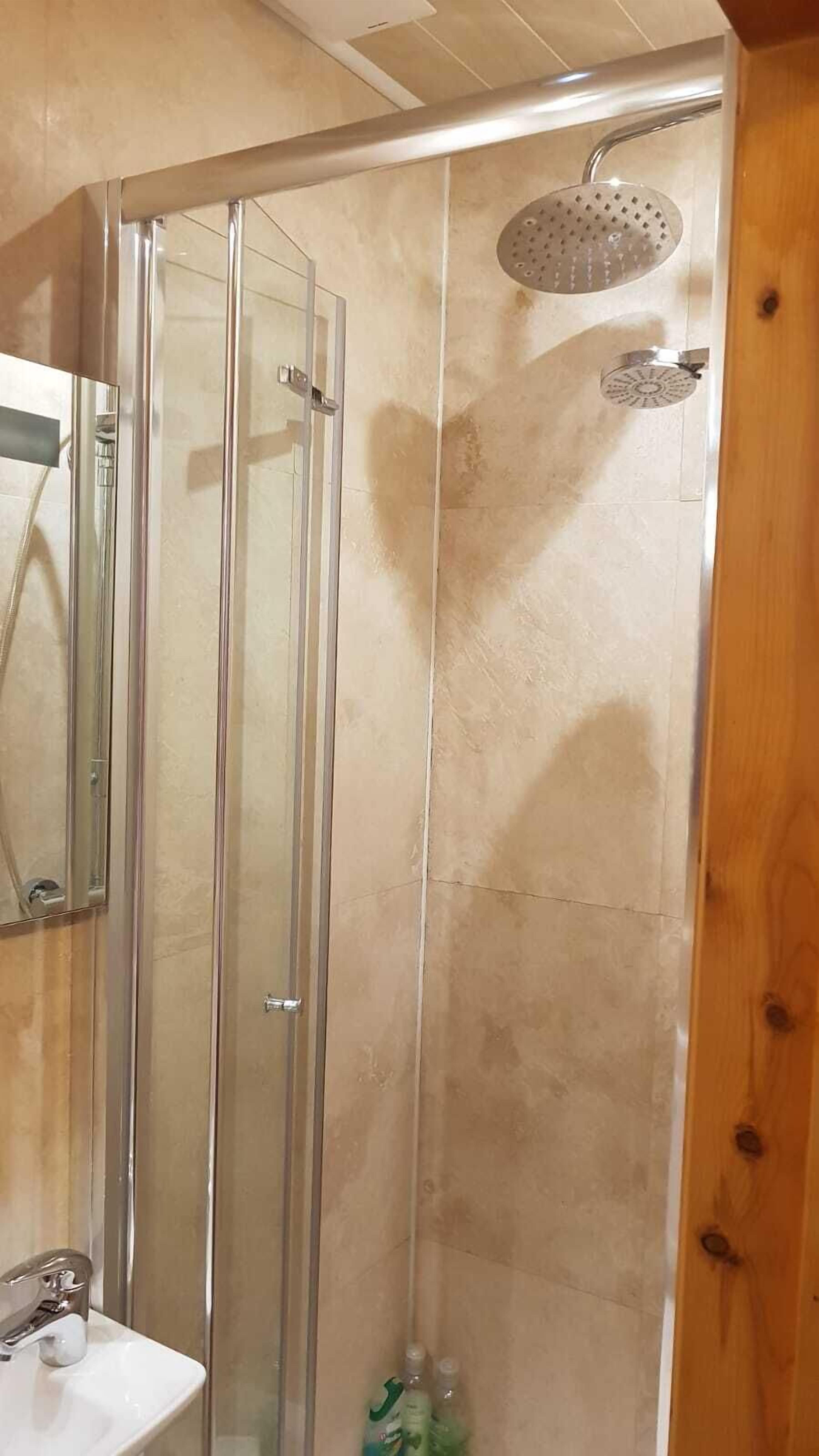 Une salle de bain avec une douche à parois de verre, un lavabo et un miroir.