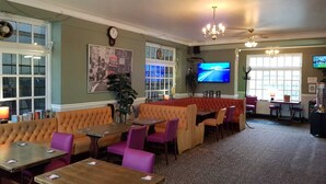 Un restaurante con cabinas y mesas, un televisor y un amplio ventanal.