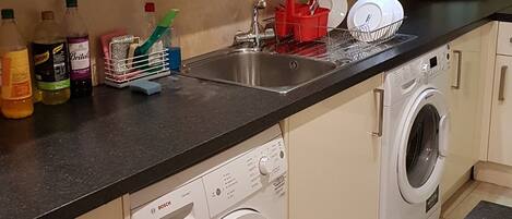 A kitchen with a Bosch washing machine, a toaster, and various kitchen items on the counter.