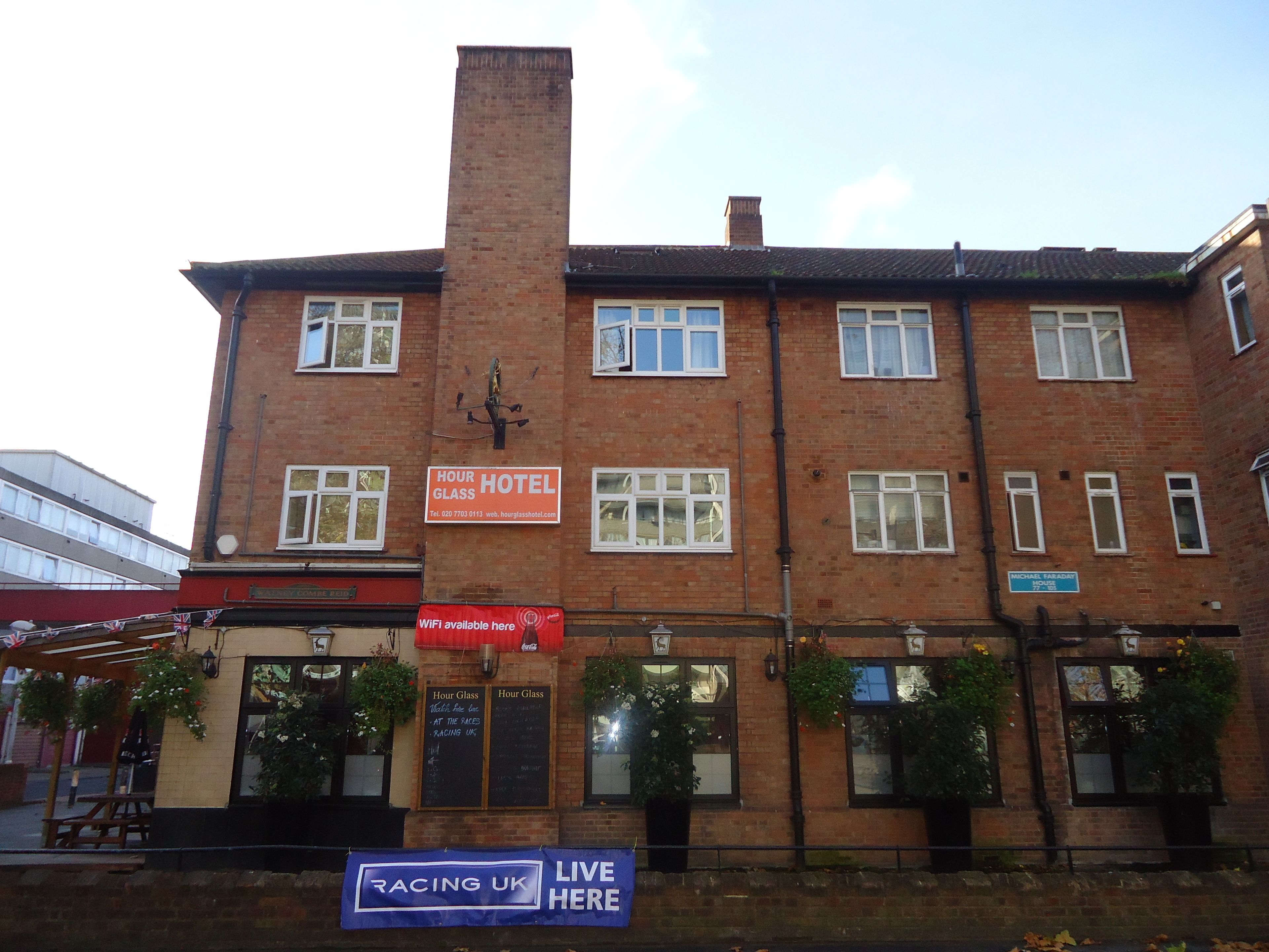 A brick building with a sign for 'Hour Glass Hotel' and a 'Racing UK Live Here' banner.
