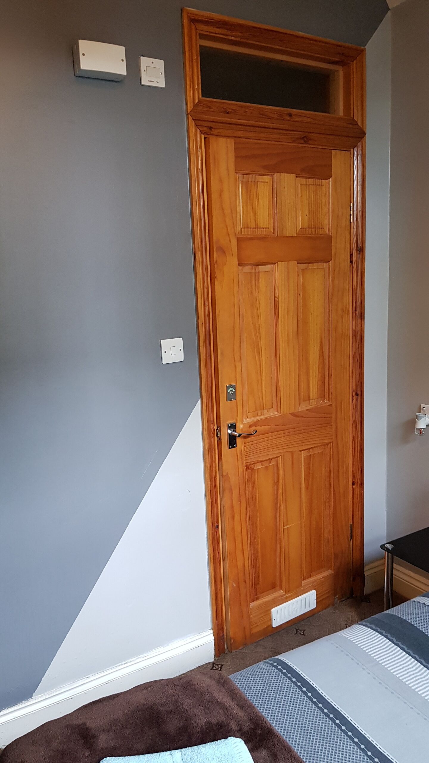 A room with a wooden door, a white radiator, a brown rug, and a patterned rug.