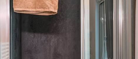 A modern shower area with a glass door, a towel hanging on the wall, and a logo for 'Club del Sole'.