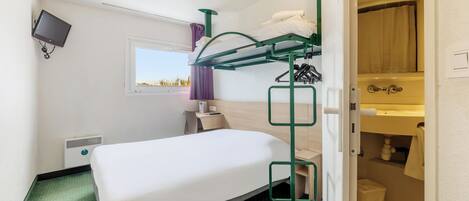A compact hotel room with a bunk bed, a single bed, a small bedside table, a TV, a window with a view, and a bathroom with a shower and sink.