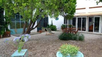 A patio area with a table and chairs, a small tree, and a potted plant.