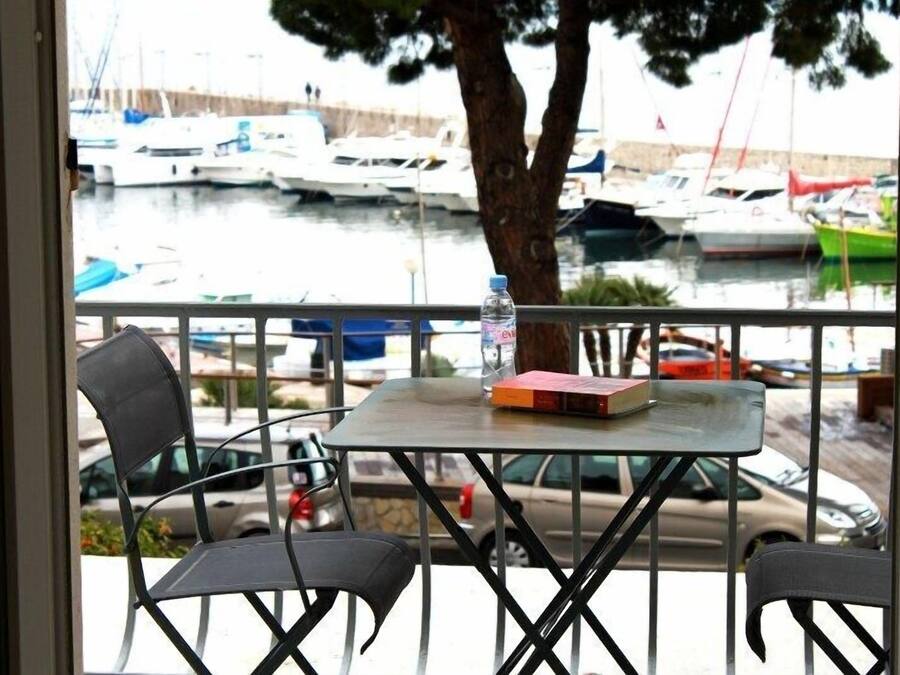 A balcony with a table, chairs, and a view of a marina with boats.