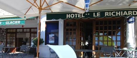 A hotel named "HOTEL LE RICHIARDI" with outdoor seating and a sign for "BAR - GLACIER".