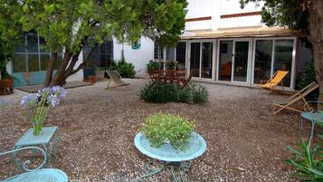 A patio area with a table and chairs, surrounded by gravel, and a building with a glass door in the background.
