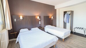 Habitación de hotel con dos camas, un radiador, un armario y un tendedero.