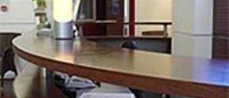 A reception desk with a lamp, a plant, and a door in the background.