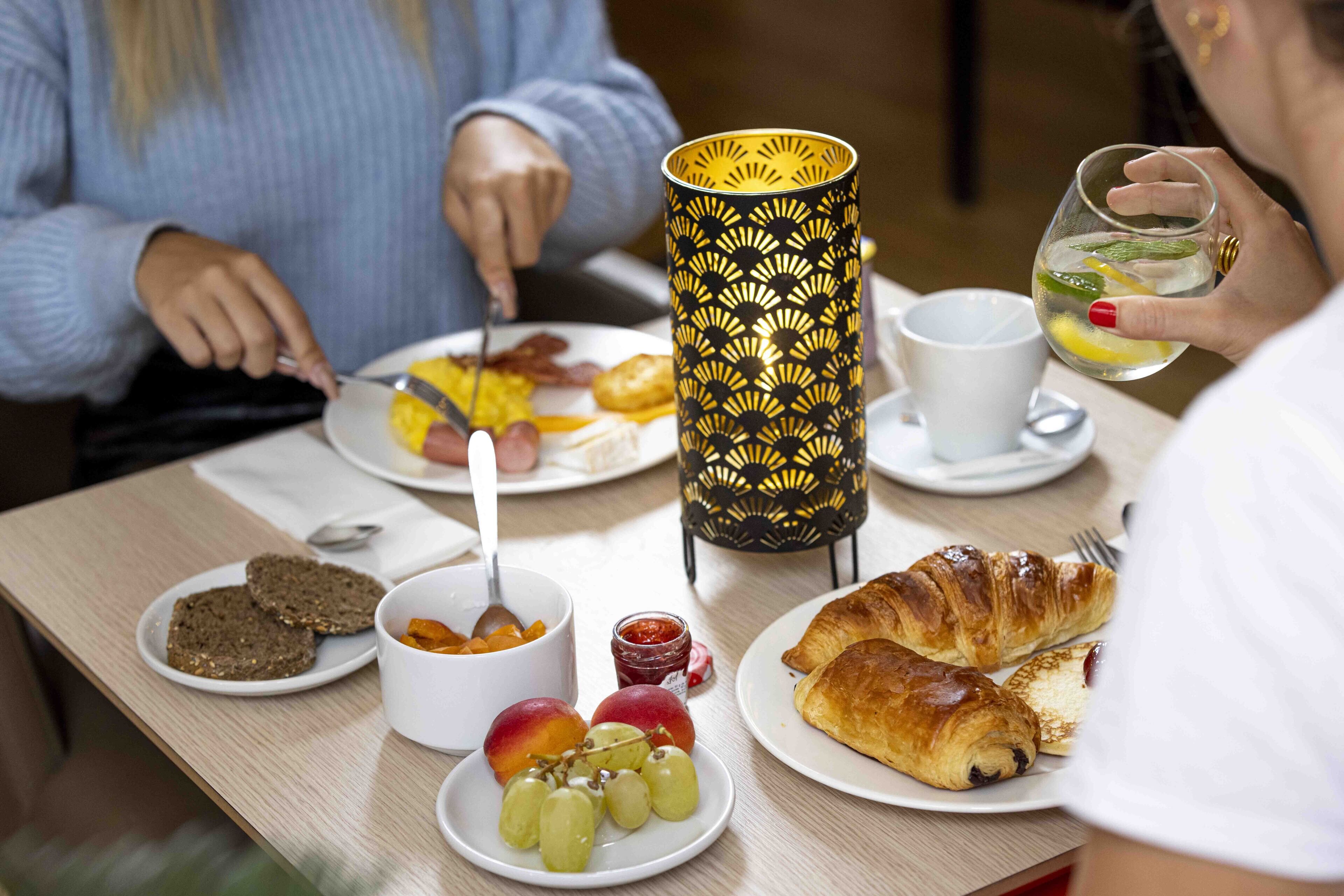 A breakfast setting with plates of food, a candle, and a cup.