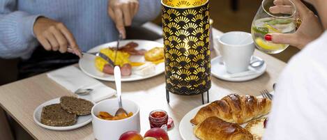 A breakfast setting with plates of food, a candle, and a cup.