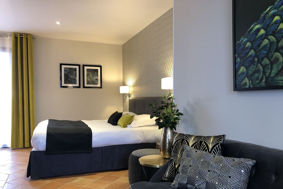 Una habitación de hotel con una cama, un sofá, una lámpara y un cuadro en la pared.