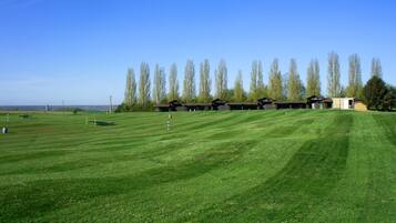 Un campo de golf bien cuidado con numerosos búnkeres y un club house.
