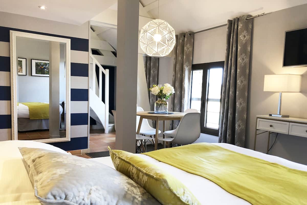 Una habitación de hotel con una cama, un escritorio, una silla, un televisor y un espejo.