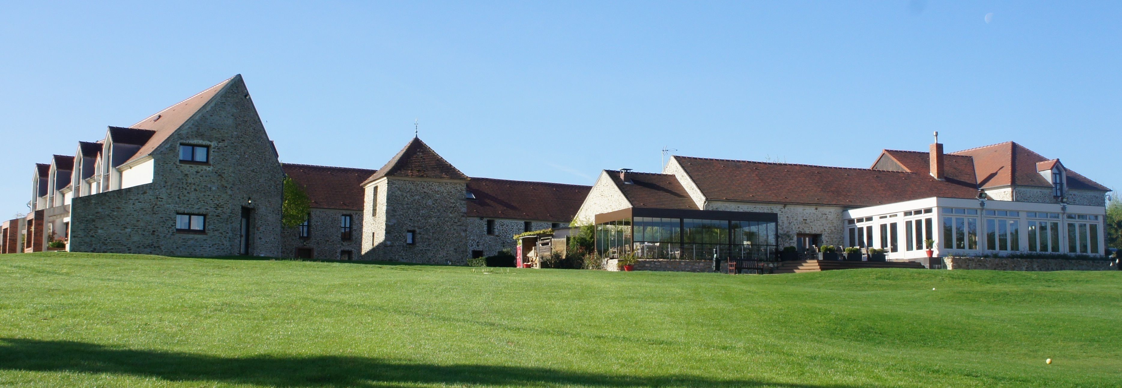 A stone building with multiple pitched roofs and a large glass conservatory.