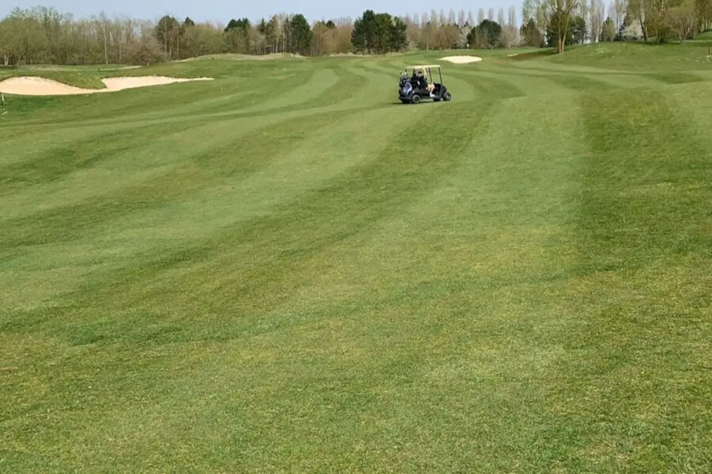 A golf course with a golf cart on a well-maintained green.