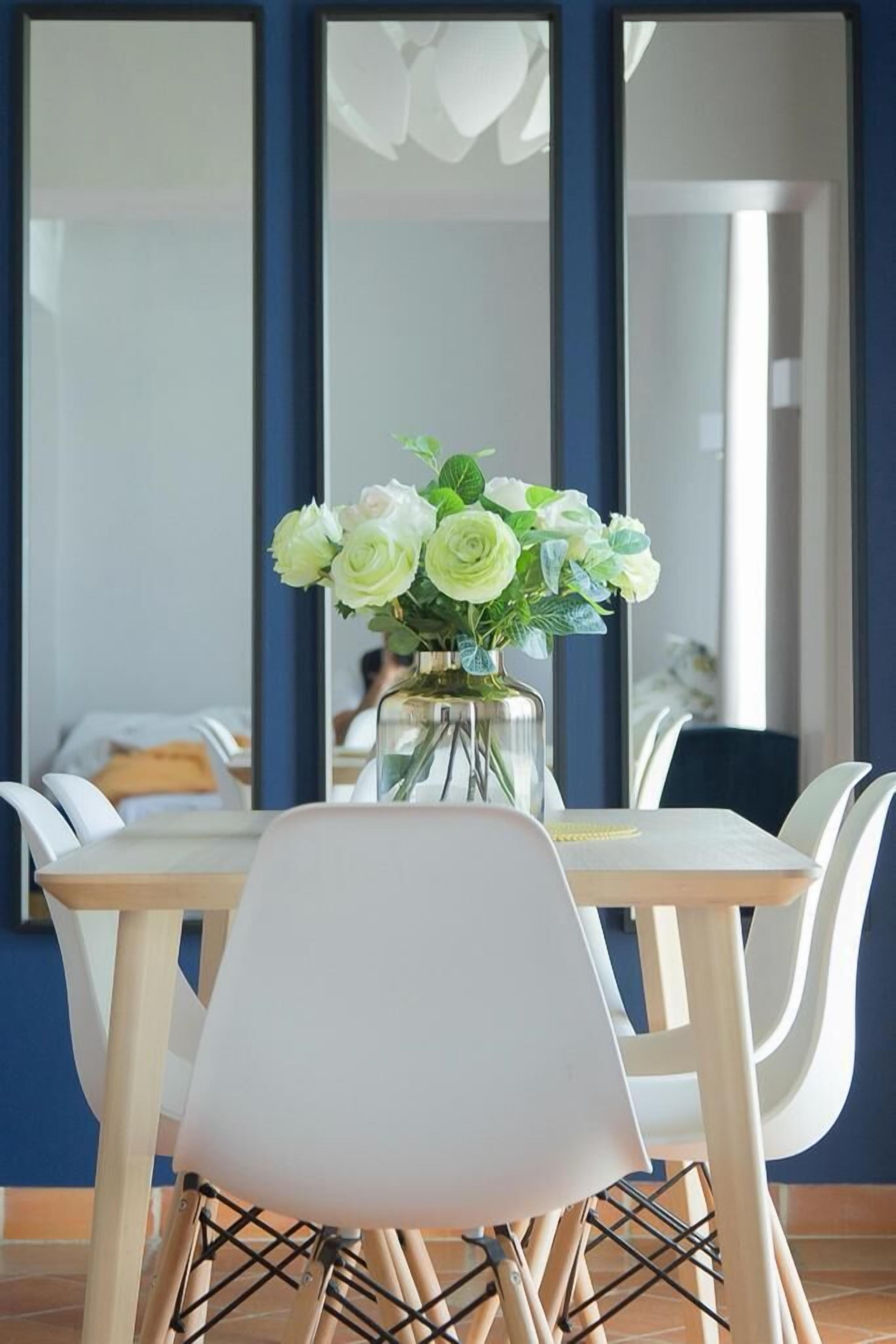 A dining area with a table, chairs, and a vase of flowers.