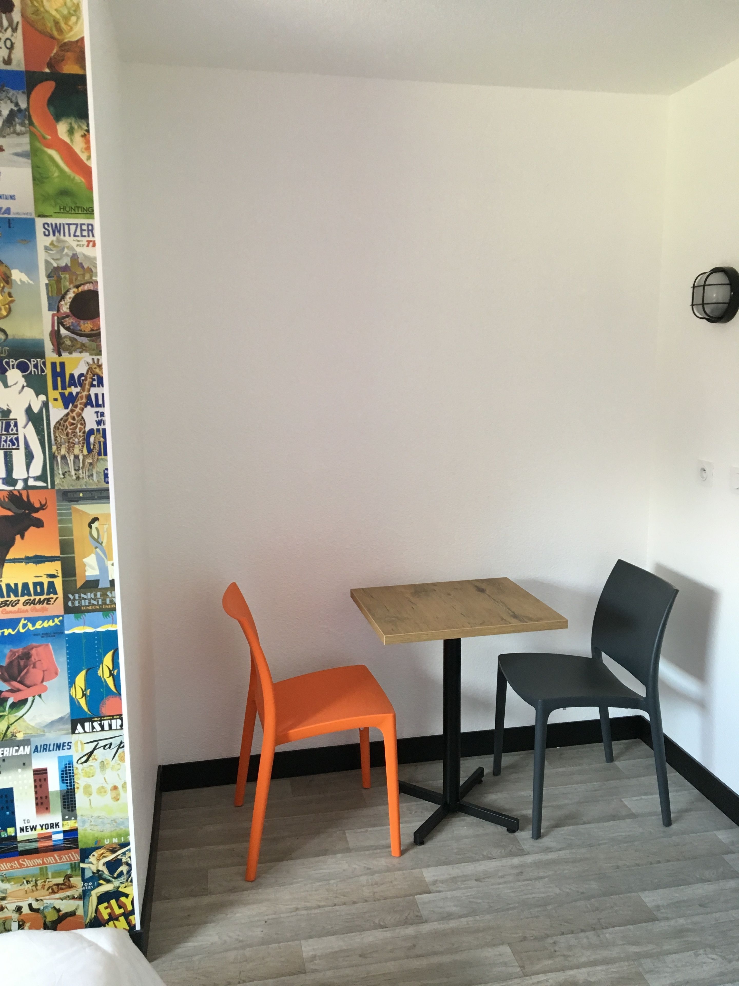 A small room with a wooden table and two chairs, one orange and one gray.
