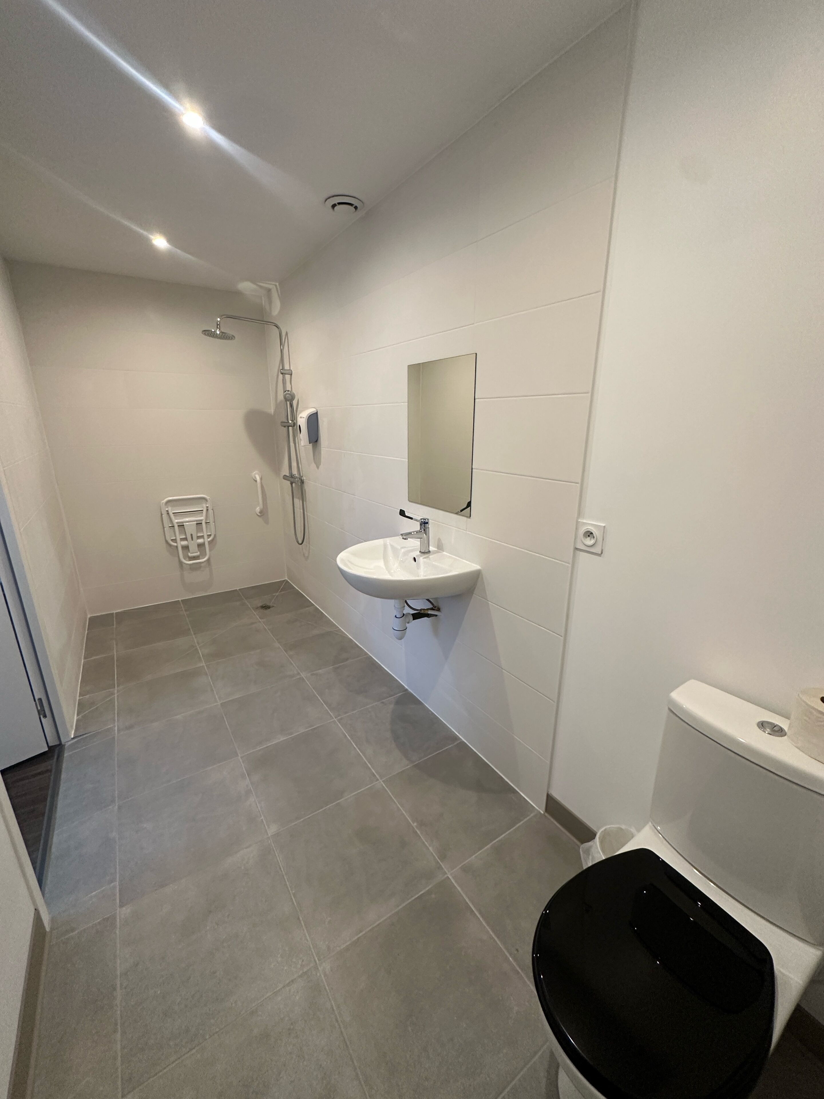 Un baño con ducha, lavabo, espejo, inodoro y toallero.
