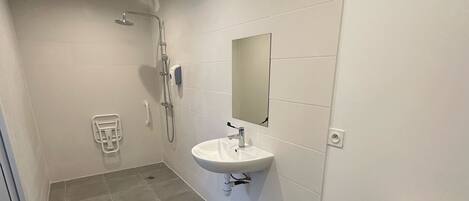 A bathroom with a shower, sink, mirror, toilet, and a towel rack.