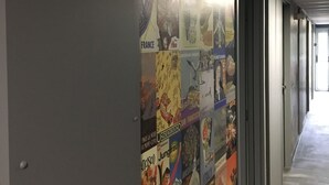 A hallway with a wall decorated with various travel posters.