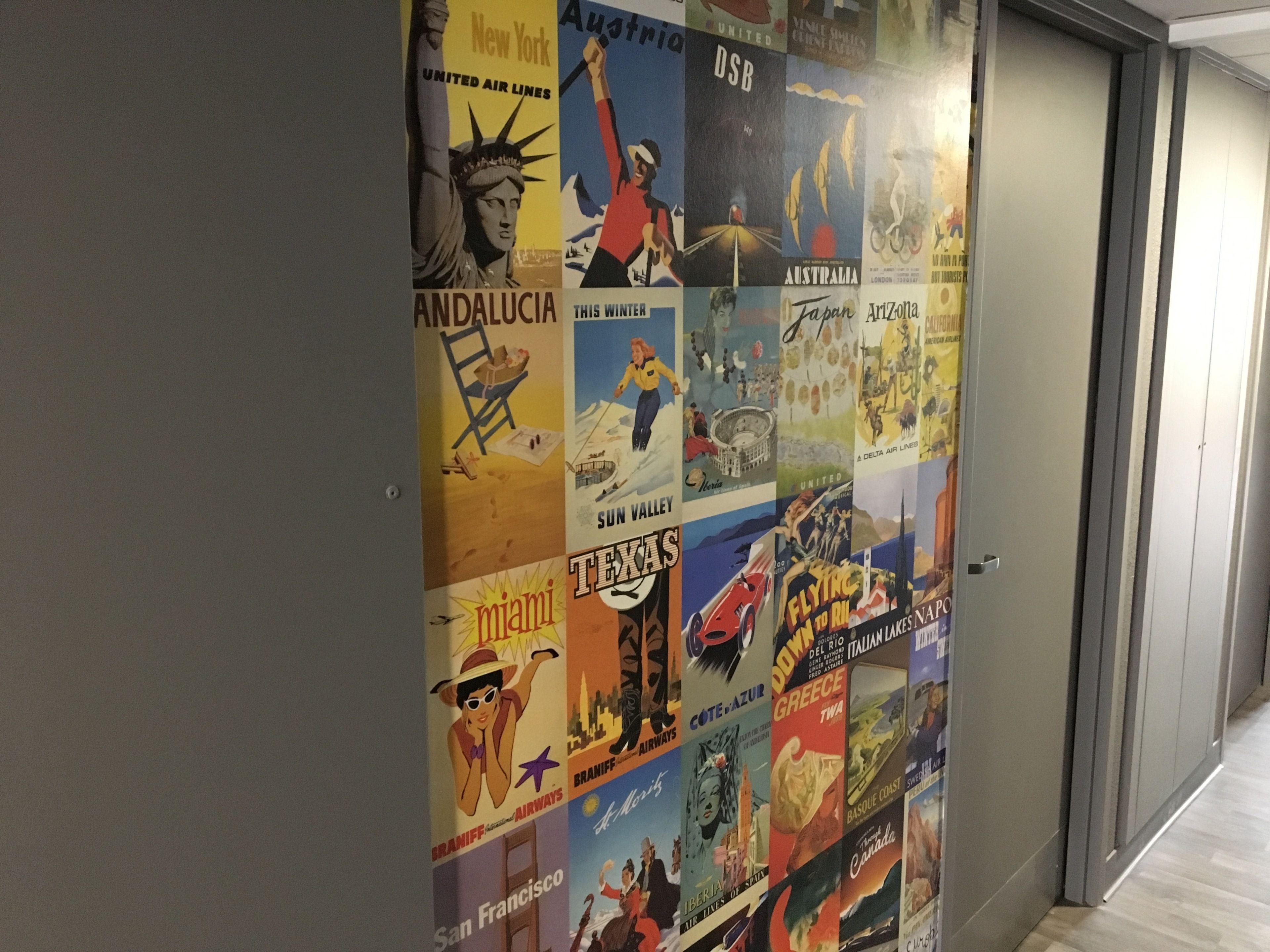 A wall with vintage travel posters of various destinations.