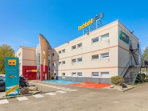 A hotel with a prominent sign, a parking area, and a staircase leading to the entrance. - hotelF1 Strasbourg La Vigie (Ostwald)