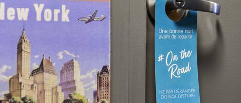 A door with a blue hotel tag featuring a cityscape and a message in French.