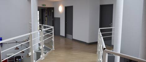 Ein moderner Hotelkorridor mit Holzboden, weißen Wänden und einer Glasumlaufung.