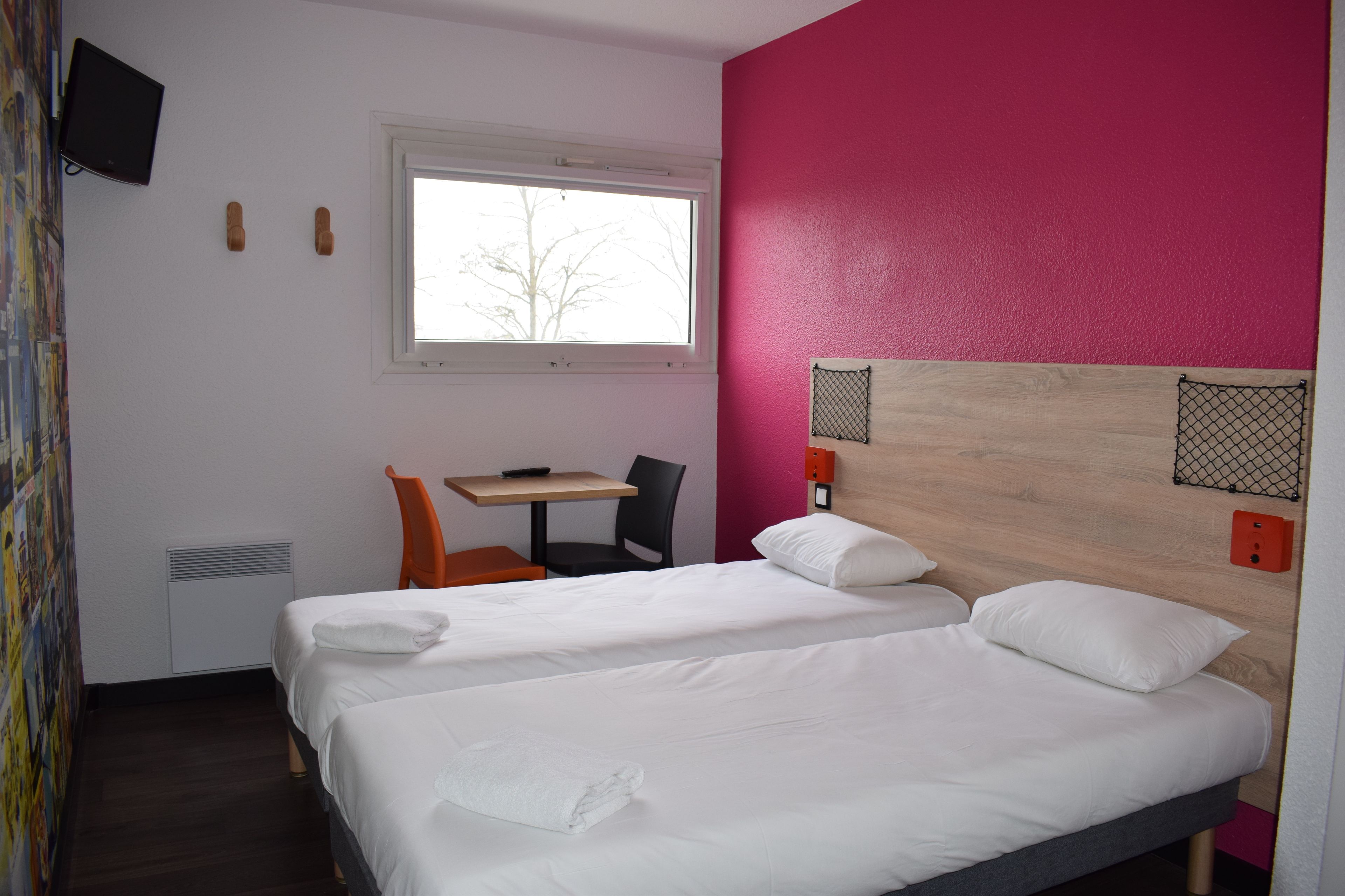 Habitación de hotel con dos camas, un escritorio y una silla.