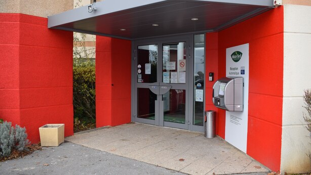 A building entrance with a red wall, a glass door, and a payment kiosk. - hotelF1 Bourges Le Subdray (Le Subdray)