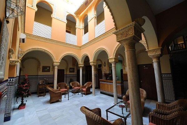A spacious courtyard with arches, wicker furniture, and a Christmas tree. - Zaida (Seville)
