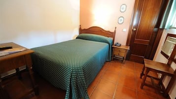 A bedroom with a wooden bed, a bedside table, a chair, and a desk.