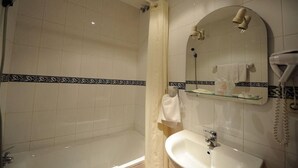 A bathroom with a bathtub, a sink, a mirror, and a hairdryer. - Zaida (Seville)