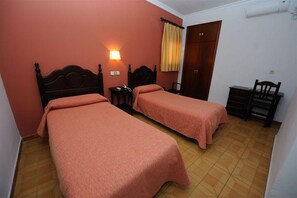 A room with two beds, a desk, and a wardrobe. - Zaida (Seville)