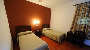 A room with two single beds, a nightstand, a dresser, and a wall-mounted lamp. - Zaida (Seville)
