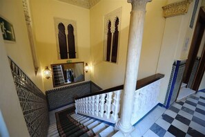A staircase with a checkered floor, a white balustrade, and a column. - Zaida (Seville)
