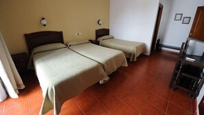 A hotel room with two single beds, a wooden nightstand with a lamp, a small table with a chair, and a wardrobe. - Zaida (Seville)