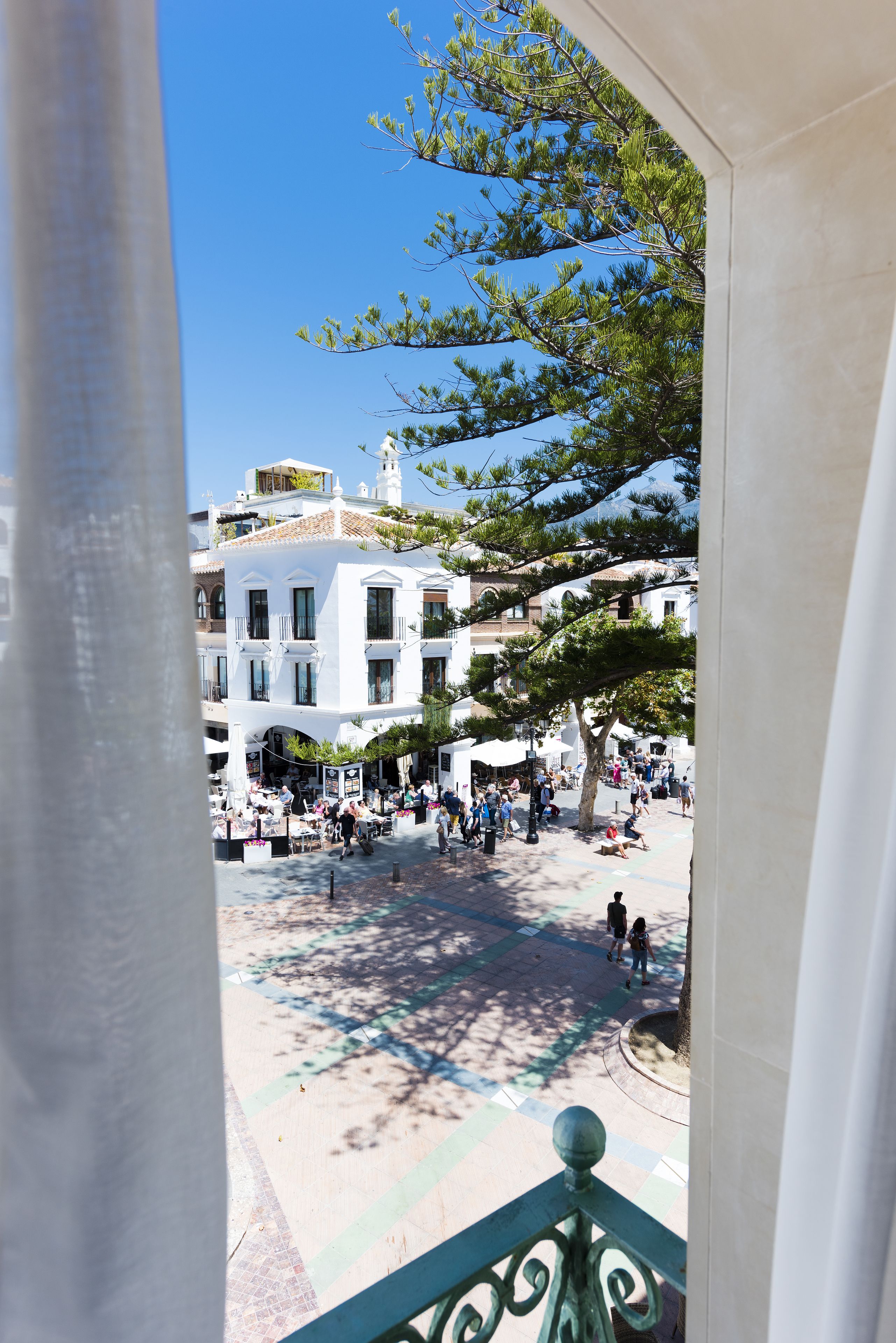 Un patio con suelo de baldosas, rodeado de edificios con balcones y ventanas.
